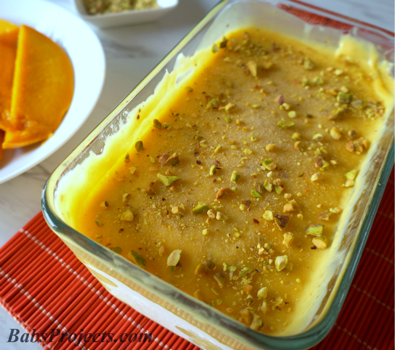 Mango Kulfi in a rectangular glass baking pan with sliced mangoes on the side
