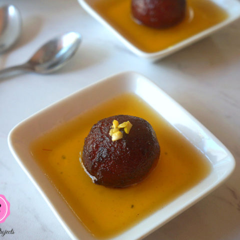 Individual Servings of Gulab Jamun on White Dishes and Spoons on the Side