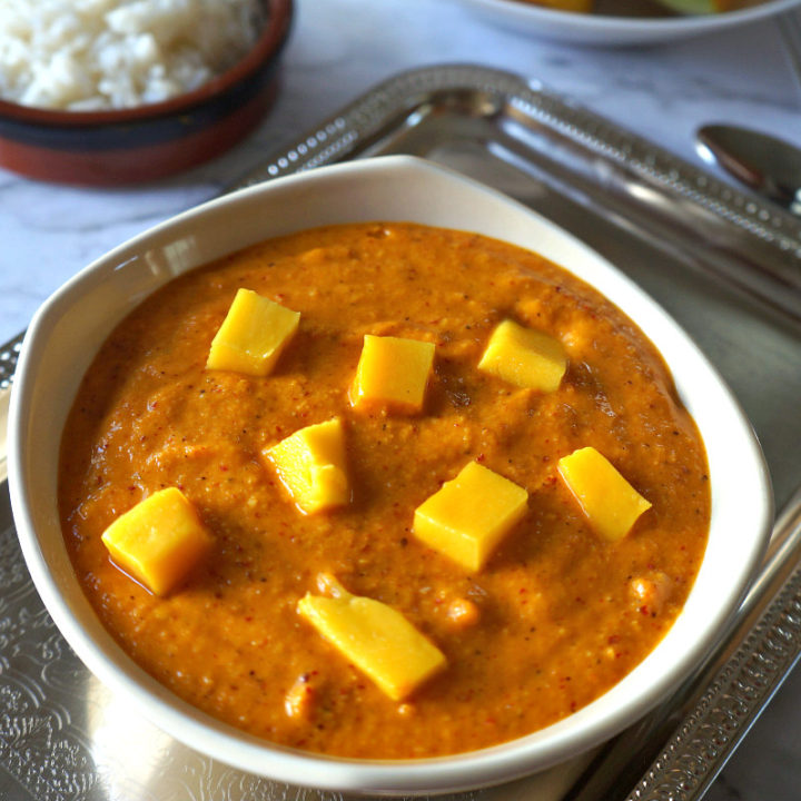 Sweet Mango Chutney in a Bowl on A Stainless Steel Tray with Rice and Mango Slices on the Side