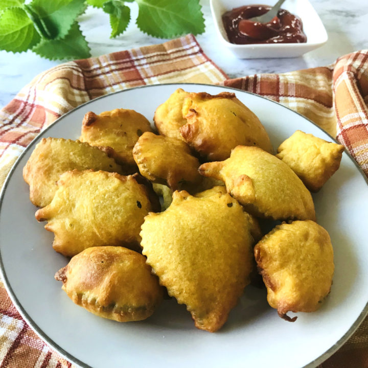 Ajwain Leaf Pakora (Sambarballi Bhajje) on a White Plate and Some Green Leaves and Ketchup on the Side