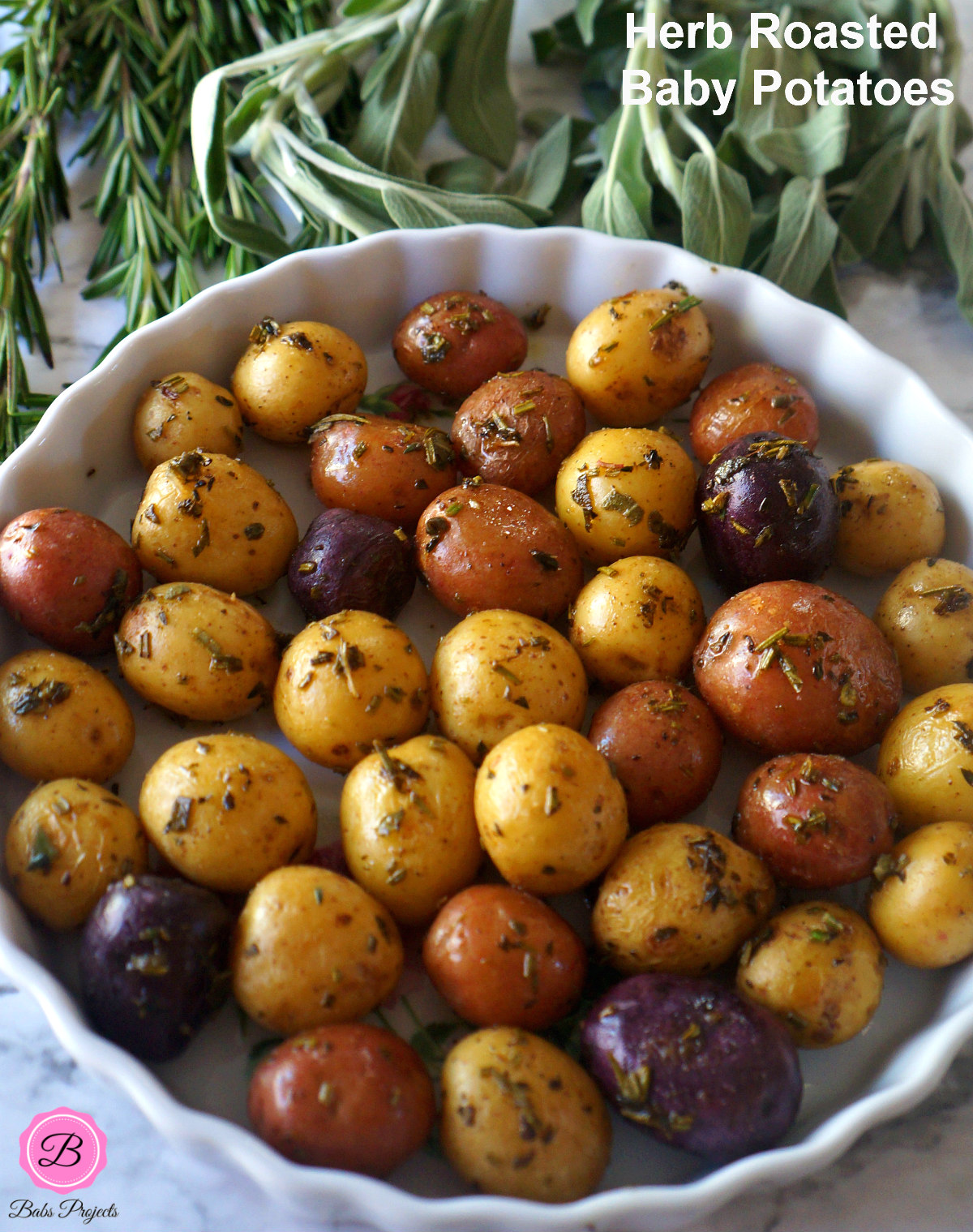 Herb Roasted Baby Potatoes in a Pie Dish Surrounded by Herbs