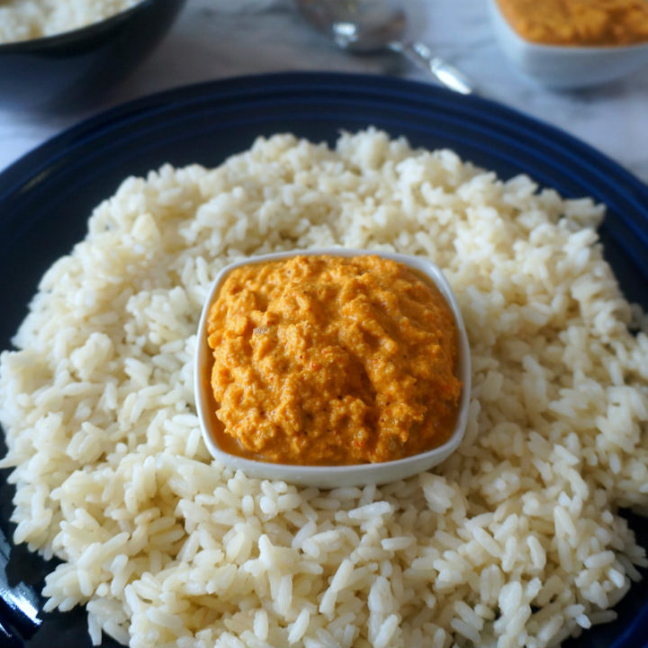 Raccha Dha Chutney in a White Bowl with Rice Around it in a Blue Plate