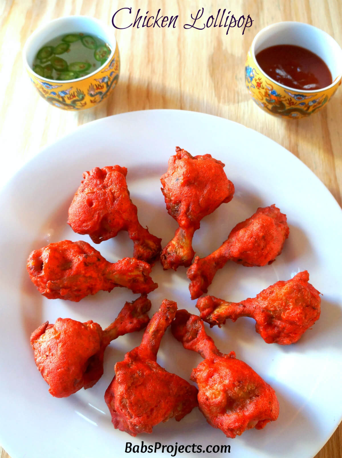 Chicken Lollipop placed in Circle on a White Plate with Two Dipping Sauces on the Side