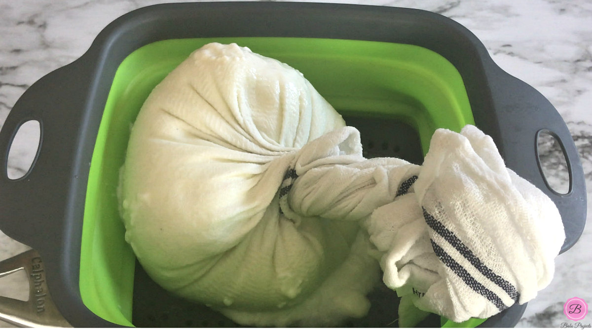 Yogurt Tied in a Towel Placed over Green Colander