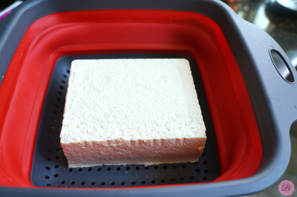 A Block of Tofu in a Red Strainer