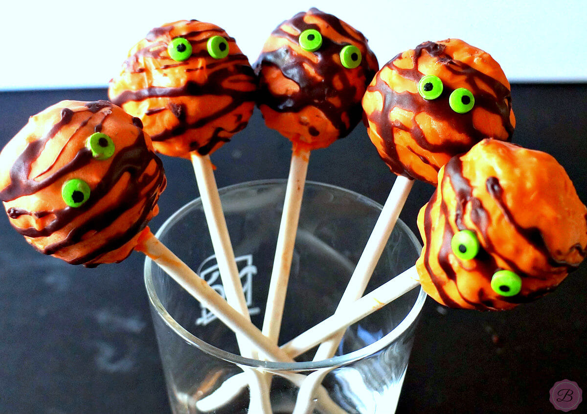 Orange Halloween Krispie Pop with Green Monster Eyes in a Glass